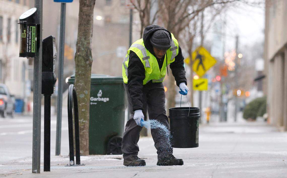 Tyron Brown with Bloomsbury Landscapes spreads ice melt outside Death & Taxes in downtown Raleigh, N.C., Sunday morning January 16, 2022.