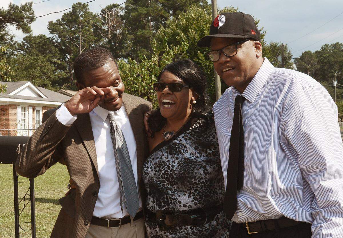 Geraldine Brown laughs as her brother Henry McCollum (left) wipes away tears as he and his brother Leon Brown (right) stand in her front yard in Fayetteville, N.C. home Wednsday, Sept. 3, 2014, the day the brothers were released from prison after their rape and murder conviction was dismissed by a Robeson County Superior Court judge. The brothers spent 30 years in prison for a crime they didn’t commit.