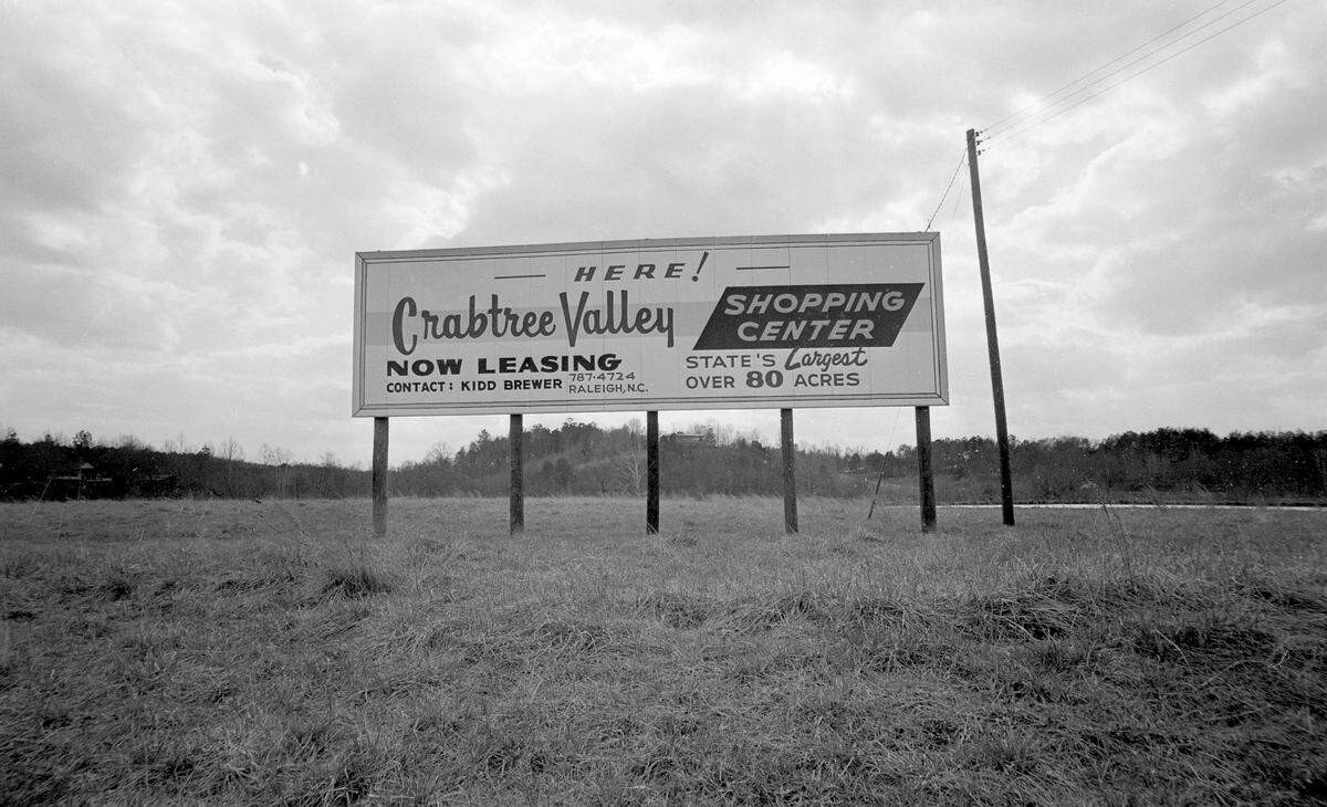 The grassy field seen here in March of 1965 would later become one of Raleigh’s most popular shopping malls. In 1971 Raleigh businessman Kidd Brewer partnered with former Raleigh Mayor Seby Jones to construct Crabtree Valley Mall on part of his flood-prone land running alongside US-70. Brewer’s house can be seen in the background just below the sign, perched high above his future development. The mall opened in August of 1972