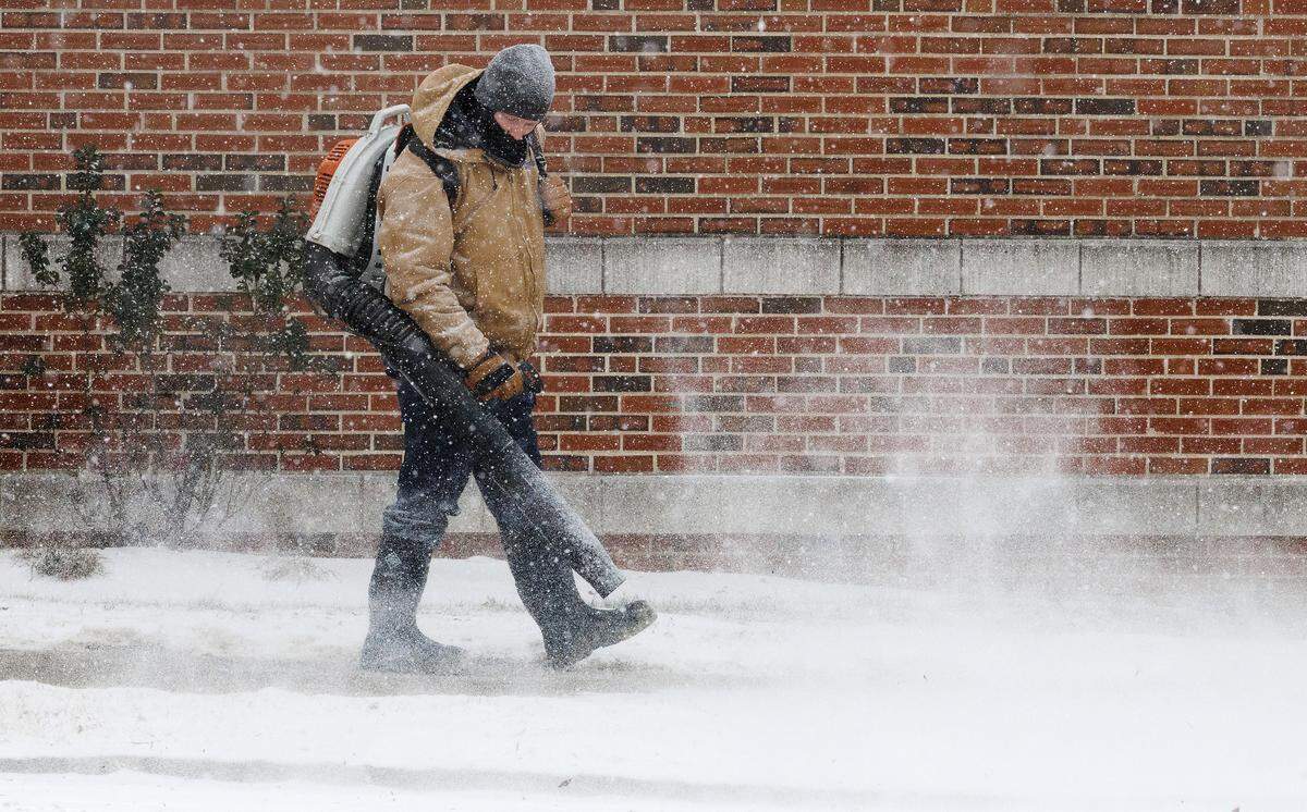 Logan Cano blows snow from a sidewalk along Broadway Street on Saturday, Jan. 31, 2026, in Durham, N.C.