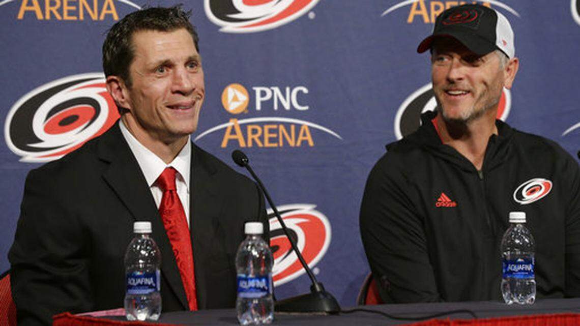 FILE - In this May 9, 2018, file photo, Carolina Hurricanes new head coach Rod Brind’Amour, left, smiles with Hurricanes owner and CEO Tom Dundon during an introductory NHL hockey news conference in Raleigh, N.C. Brind’Amour is one of only four coaches in the four major pro sports to earn the top job of the team with which he won a championship as a player. (AP Photo/Gerry Broome)