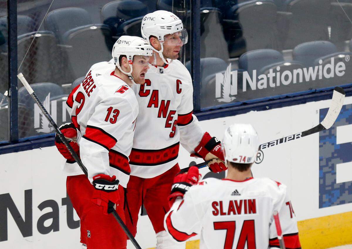 Carolina Hurricanes forwards Warren Foegele, left, and Jordan Staal and defenseman Jaccob Slavin celebrate Foegele’s goal against Columbus on Feb. 7, 2021. All three have spent time this season on the NHL COVID-19 protocol list. (AP Photo/Paul Vernon)