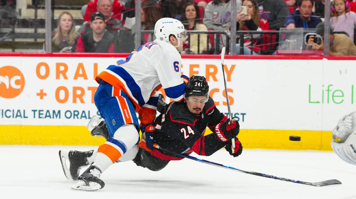 Mar 30, 2025; Raleigh, North Carolina, USA; Carolina Hurricanes center Seth Jarvis (24) gets the shot away against New York Islanders defenseman Ryan Pulock (6) during the first period at Lenovo Center. Mandatory Credit: James Guillory-Imagn Images