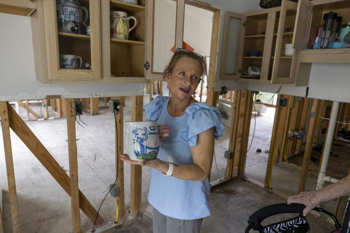 Jennifer Johnson clutches a prized piece of her pottery collection that remains in the gutted kitchen of her home in Carrboro. Flood water, following heavy rain from Tropical Storm Chantal in July, forced Johnson and her family from their home. They are living in a rental while waiting for repairs to be completed to their home. 