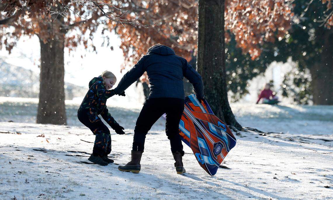 Alesso Rosa, 8, helps his dad Paolo up an icy patch while sledding at Dix Park in Raleigh, N.C., Saturday morning, Jan. 11, 2025.