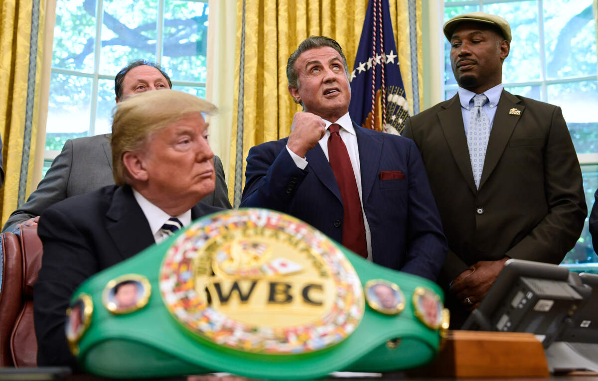 President Donald Trump, left, and heavyweight champion boxer, Lennox Lewis, right, watch as Sylvester Stallone gestures in the Oval Office of the White House in Washington, Thursday, May 24, 2018, where Trump granted a posthumous pardon to Jack Johnson, boxing's first black heavyweight champion.