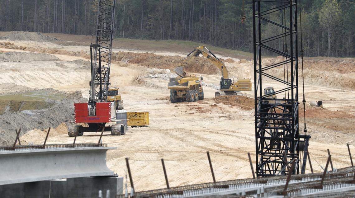 Concrete girders for twin bridges that will carry N.C. 540 over Brushy Branch, with the path of the highway in the distance. The final 10-mile section of the Triangle Expresway toll road is scheduled to open in late 2028.