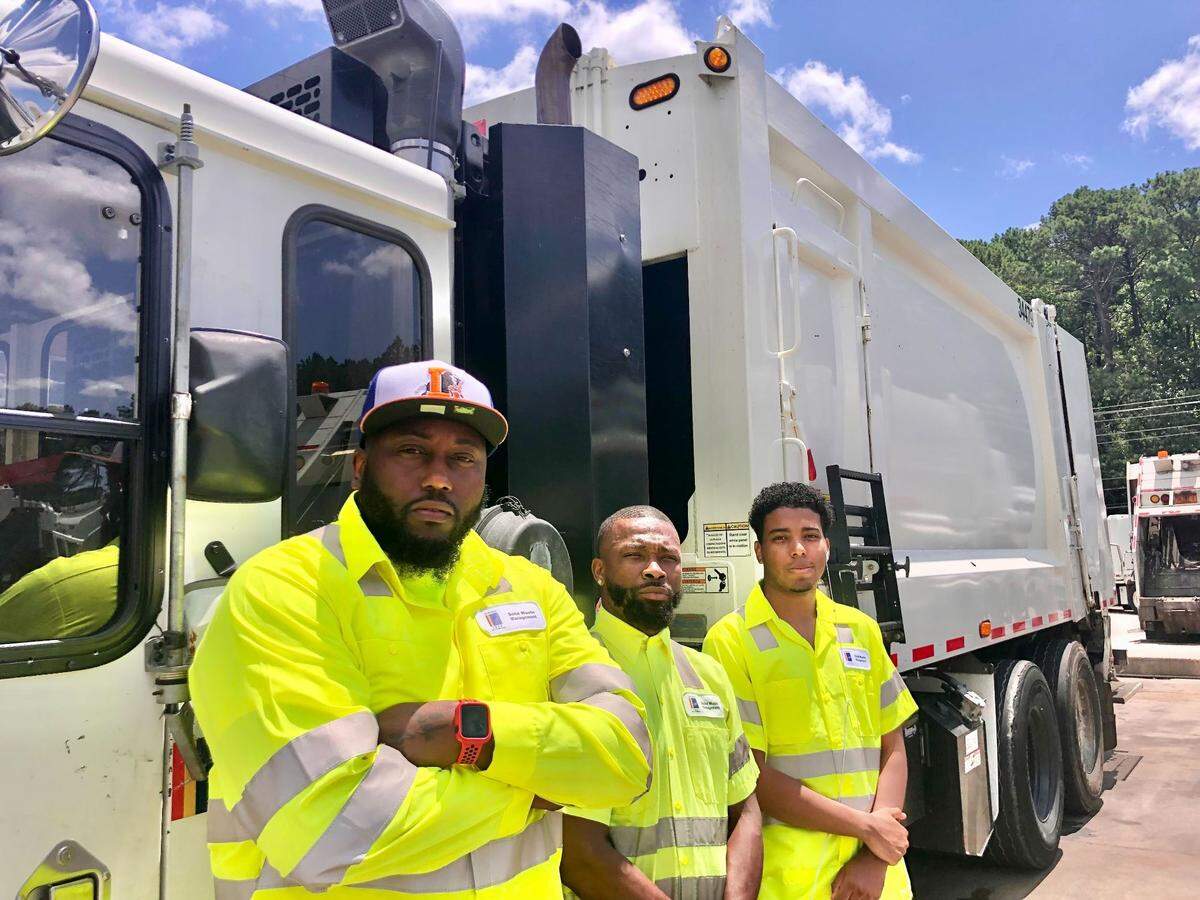 Sanitation workers Kenneth Parker, Harold Byrd and Keshaun Sloan stand for a photo on July 19, 2022 outside their garbage collection truck outside the offices of the Durham Solid Waste Management.