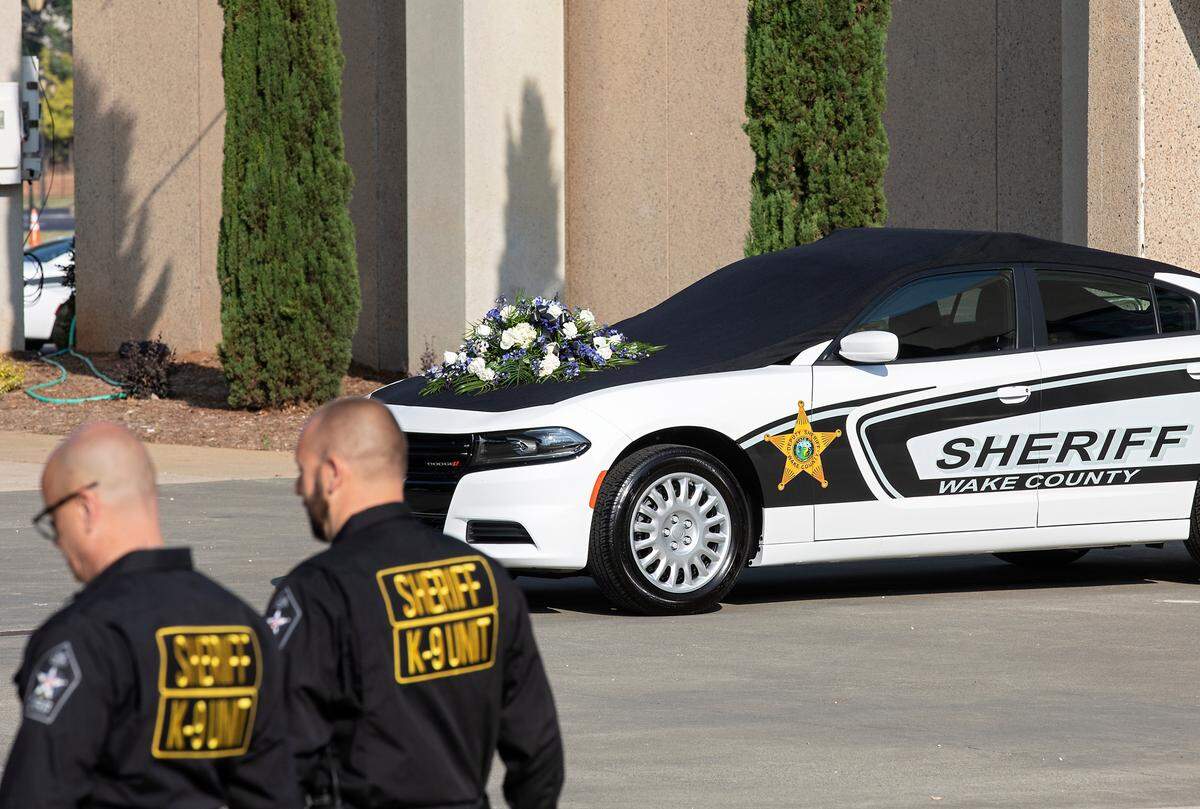 Law enforcement walks by a Wake County Sheriff vehicle draped in black prior to a memorial service for K9 Santos at the Kerr Scott Building on Wednesday, June 14, 2023, in Raleigh, N.C. K9 Santos, a German shepherd, was accidentally shot and killed by a Knightdale police officer after a traffic stop in May. Santos joined the Wake County Sheriff’s Office in 2016 and was the department’s longest serving K9.