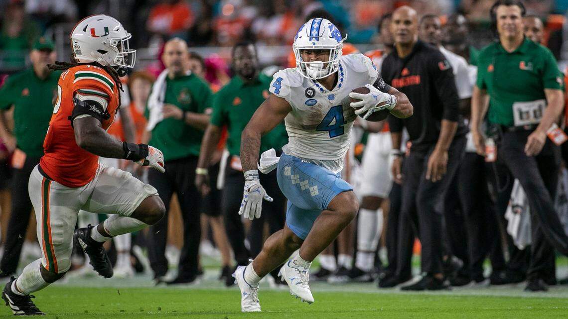 North Carolina’s Caleb Hood (4) looks for running room against Miami’s Jahfari Harvey (12) after a pass completion from quarterback Drake Maye in the fourth quarter on Saturday, October 8, 2022 at Hard Rock Stadium in Miami Gardens, Florida.
