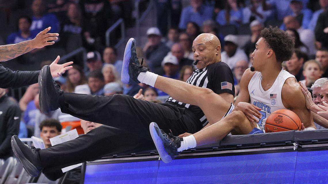North Carolina's Seth Trimble sits next to official Bill Covington atop the scorers table after careening out of bounds during the first half of the Tar Heels’ ACC Tournament quarterfinal game against Clemson on Thursday, March 12, 2026, at the Spectrum Center in Charlotte, N.C.