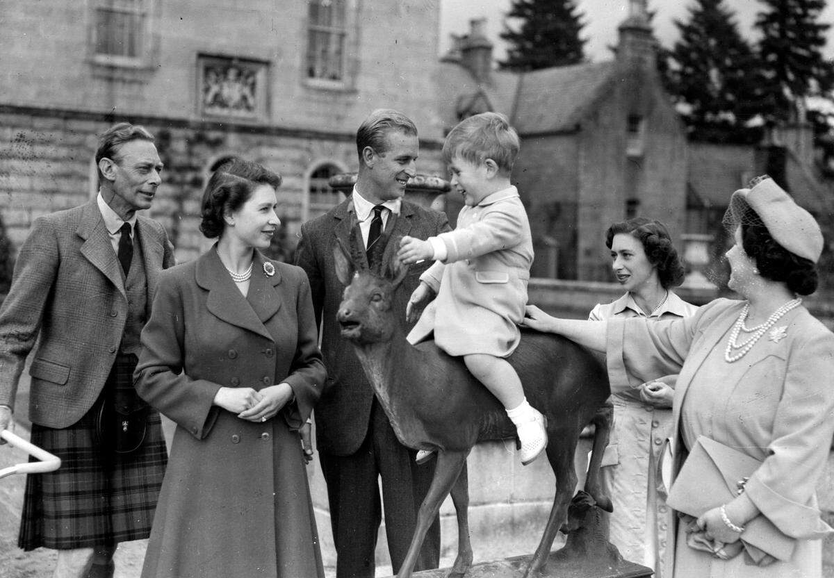 Britain’s Prince Charles, watched by, from left, King George VI, Princess Elizabeth, Prince Philip, Princess Margaret and Queen Elizabeth, sits on a sculpture of a deer in the grounds of Balmoral Castle, Scotland, in August 1951.
