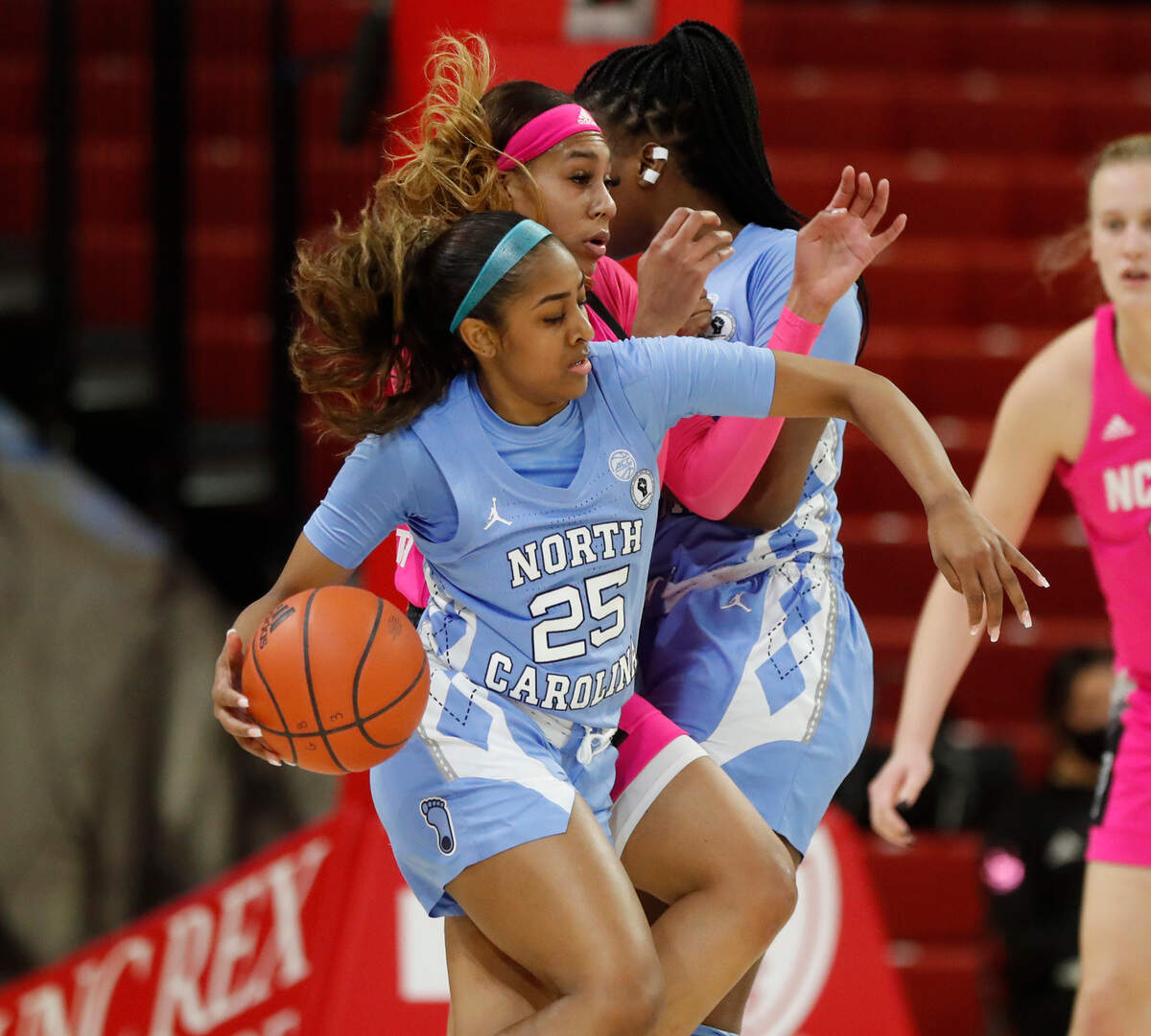 North Carolina’s Deja Kelly (25) drives around N.C. State’s Jakia Brown-Turner (11) during the first half of N.C. State’s game against UNC in the annual Play4Kay game at Reynolds Coliseum in Raleigh, N.C., Sunday, February 21, 2021.
