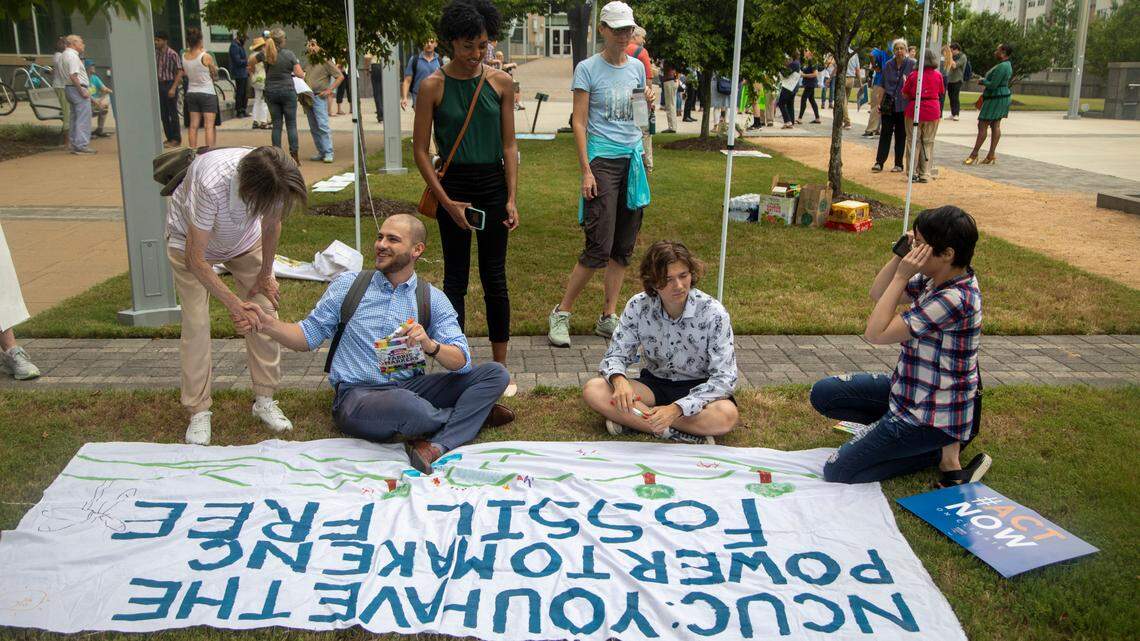Demonstrators sign a banner prior to a rally outside the Durham County courthouse Monday July 11, 2022 as the N.C. Utilities Commission travels across North Carolina, hearing public comments on a proposal that will guide how the state slashes emissions from the power sector.