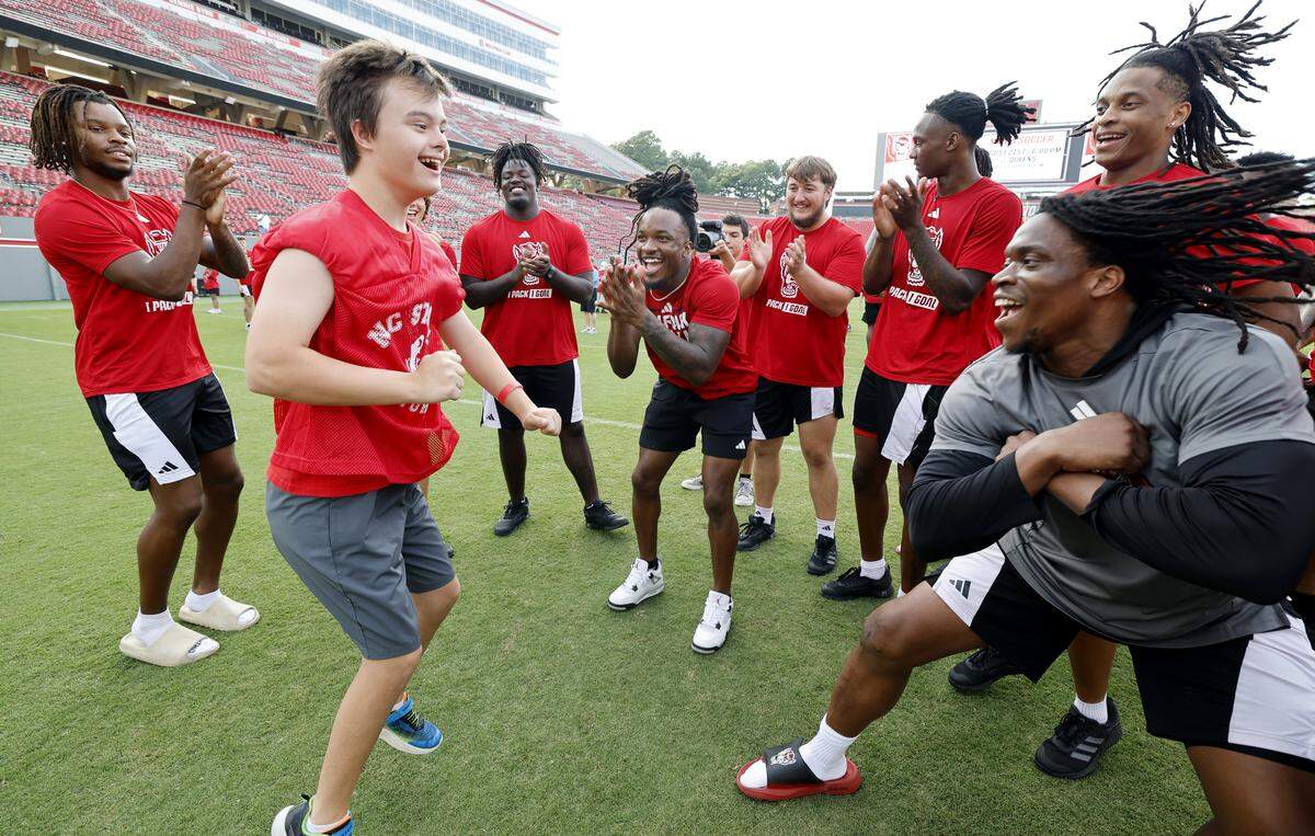 Nick Houck celebrates with N.C. State football players after scoring a touchdown during the WolfpackÕs Victory Day at Carter-Finley Stadium Saturday, August 16, 2025. N.C. State hosted its annual event with GigiÕs Playhouse to give individuals with disabilities a chance to experience football.