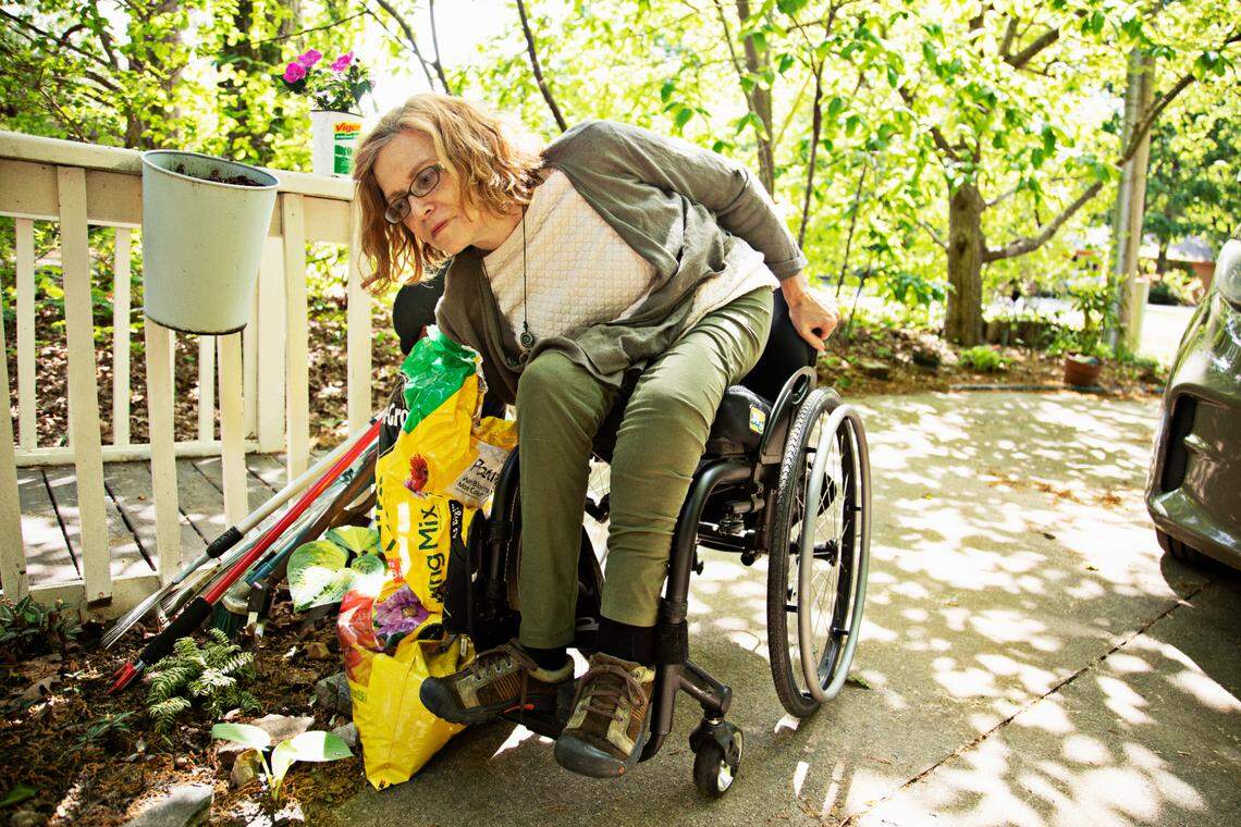 Pam Dickens reaches into a bag of potting soil as she prepares to plant impatiens in pots along the railing of her porch in Hillsborough on Friday, April 29, 2022.