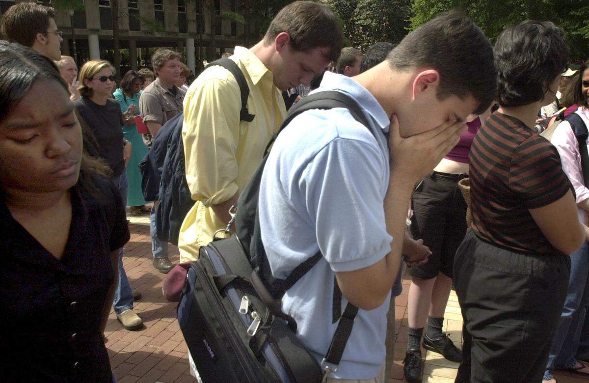 N.C. State senior Aaron Allsbrook holds his hands over his face while saying a prayer during a vigil in the brickyard on the N.C. State campus. Freshman Kiwanna Townsend is at left. The noon vigil was held after terrorist attacks in New York City and Washington, D.C Tuesday morning September 11, 2001.
