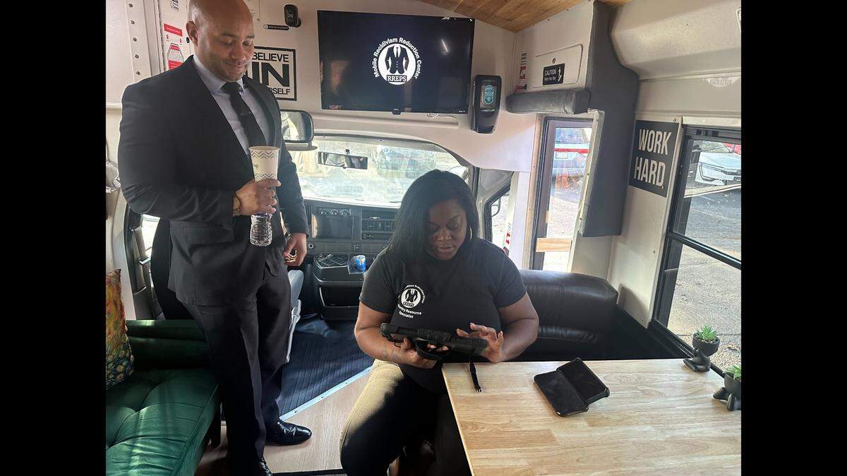 Kerwin Pittman, standing, and Ciara Levy, seated, chat on board the Mobile Recidivism Reduction Center in Raleigh on Jan. 29, 2025. Pittman created the traveling support services center this year to help the formerly incarcerated.