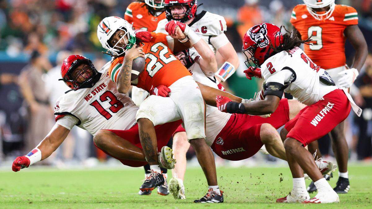 NC State’sTravali Price tackles Miami’s Girard Pringle Jr. (22) during the fourth quarter of the game at Hard Rock Stadium on November 15, 2025 in Miami Gardens, Florida. 