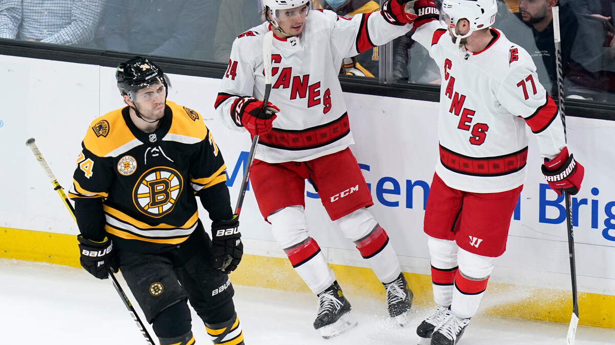 Carolina Hurricanes center Seth Jarvis, center, is congratulated by Tony DeAngelo (77) after his goal as Boston Bruins left wing Jake DeBrusk, left, skates past during the first period of an NHL hockey game, Tuesday, Jan. 18, 2022, in Boston. (AP Photo/Charles Krupa)