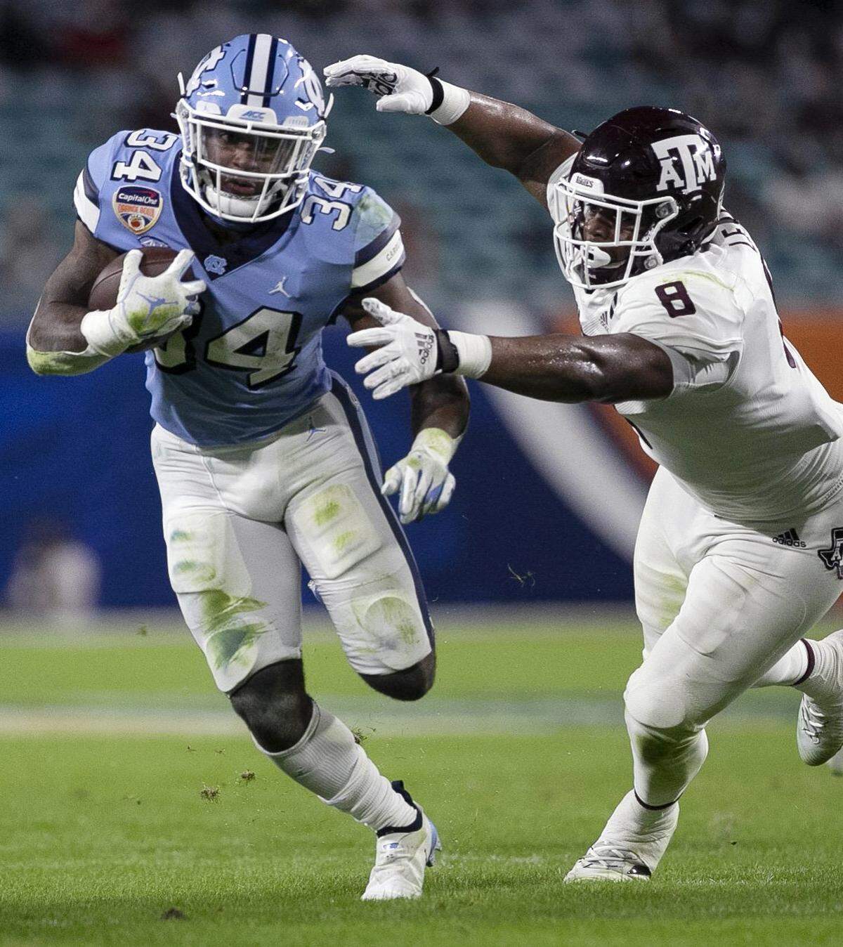 North Carolina’s British Brooks (34) picks up six yards in the first quarter ahead of Texas A&M’s DeMarvin Leal (8)  in the Capital One Orange Bowl on Saturday, January 2, 2021in Miami Gardens, Florida. Brooks rushed for 53 yards in the Tar Heels’ loss to Texas A&M. 