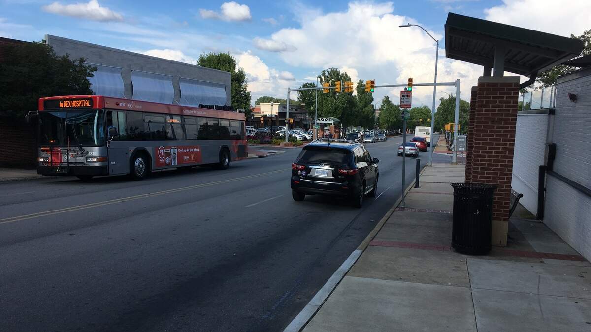 There are two bus stops along Cameron Street in Cameron Village in Raleigh. The shopping center’s owner, Regency Centers, would rather leave the traffic pattern on the street as it is, while the cycling advocacy group Oaks & Spokes would like to see the city follow through on plans to install bike lanes.