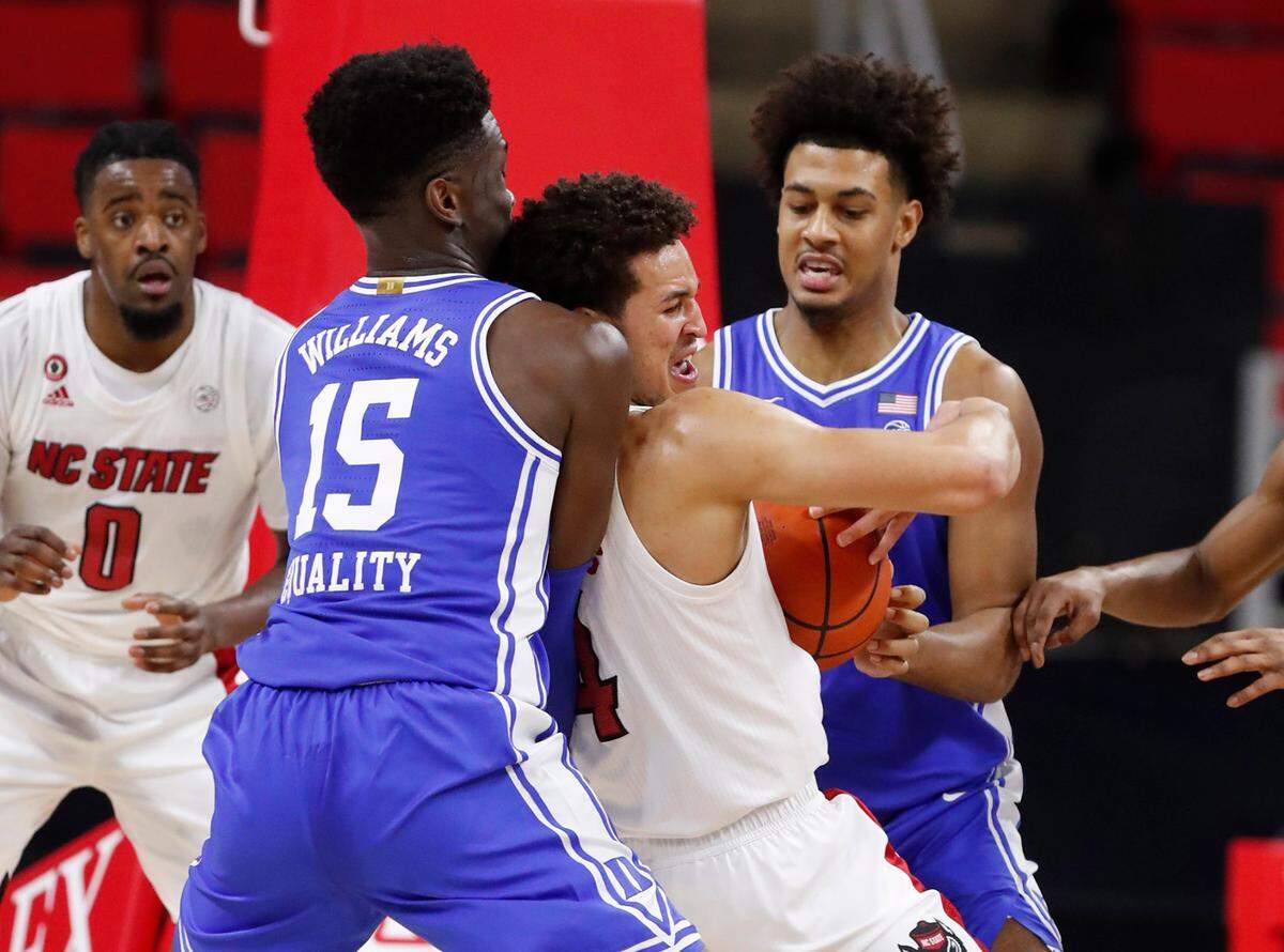 N.C. State’s Jericole Hellems (4) keeps the ball from Duke’s Mark Williams (15) and Jaemyn Brakefield (5) during the first half of N.C. State’s game against Duke at PNC Arena in Raleigh, N.C., Saturday, February 13, 2021.
