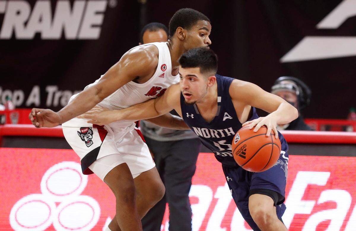 North Florida’s Jose Placer (15) drives around N.C. State’s Thomas Allen (5) during the first half of N.C. State’s game against North Florida in the Mako Medical Wolfpack Invitational at Reynolds Coliseum in Raleigh, N.C., Friday, Nov. 27, 2020.