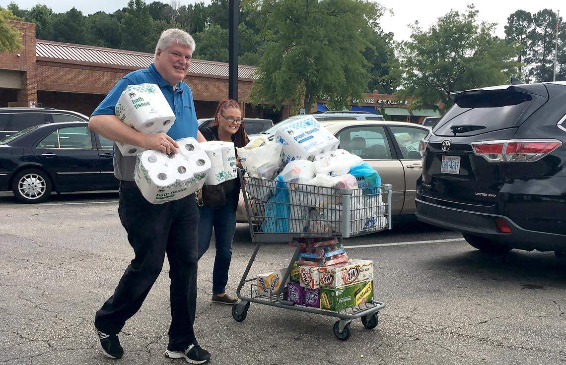 Food Lion employee Greg Partin helps a customer to her car Monday, Sept.11, 2018 at the Woodcroft shopping center in Durham, N.C.  Residents of eastern and central North Carolina are stripping grocery shelves and emptying supplies of gasoline as Hurricane Florence approaches the Old North State.