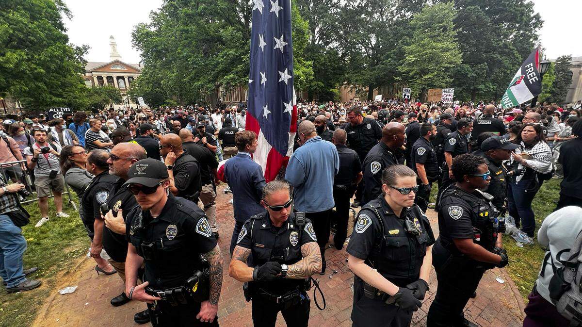 UNC interim chancellor Lee Roberts (center left), prepares to raise the United States flag after protesters replaced in with a Palestinian flag during protests on campus, Tuesday, April 20, 2024.