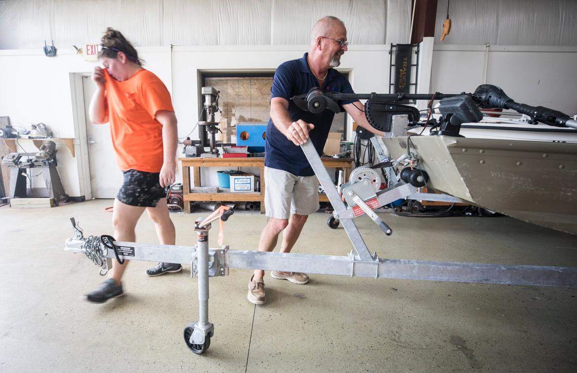 Rebecca Nelson, left, and Terry Crabtree, right, arrange boats inside the garage at Downeast Marine in Otway, N.C. in preparation for the arrival of Hurricane Isaias on Monday, Aug. 3, 2020.