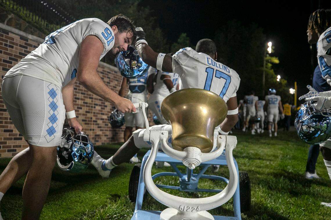 North Carolina kicker Ben Kieran (91) rings the victory bell as teammate Chris Collins (17) rides off the field to the locker room following the Tar Heels 38-35 victory over Duke on Saturday, October 15, 2022 at Wallace-Wade Stadium in Durham, N.C.