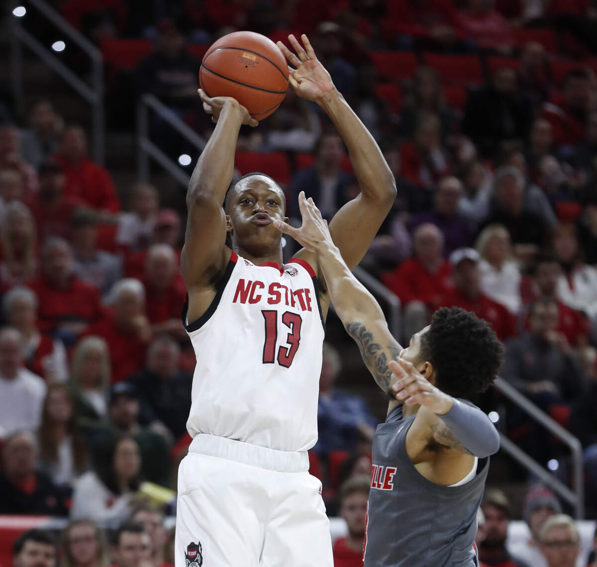N.C. State’s C.J. Bryce (13) shoots as Louisville’s Lamarr Kimble (0) defends during the first half of N.C. State’s game against Louisville at PNC Arena in Raleigh, N.C., Saturday, Feb. 1, 2020.