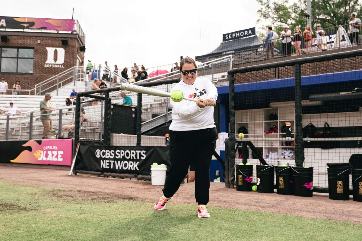 Carolina Blaze associate head coach Lindsay Leftwich swings a bat in front of the dugout at Smith Family Stadium in Durham, North Carolina, ahead of the team’s season opener on June 9, 2026. Leftwich also serves as the N.C. State head softball coach.