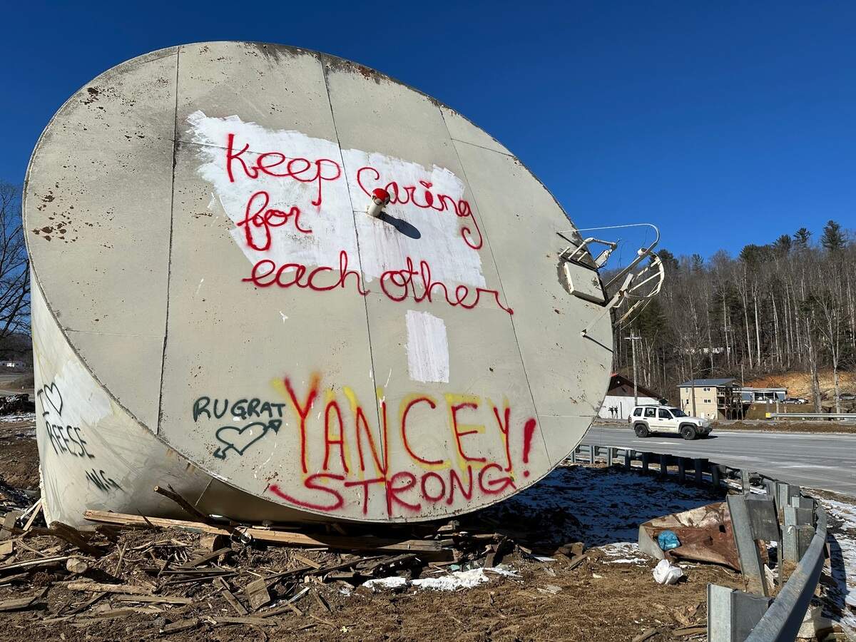 The water tank from the former Taylor Togs textile plant, seen here in January 2025, sat lodged against a culvert where the Micaville Loop road meets U.S. 19E in Yancey County, North Carolina.
