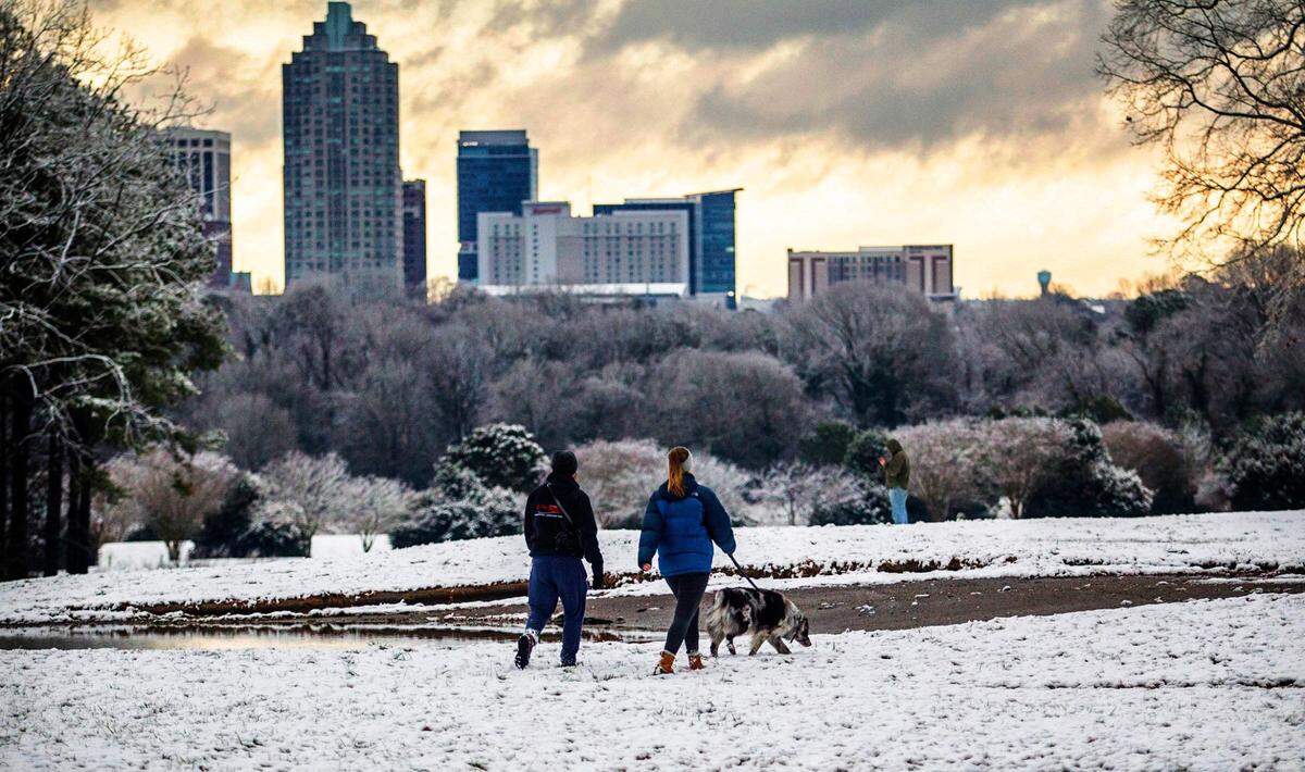 Lewis Gaffney and Katie Gilmore walk ìBode,î an Australian Shepherd at Dorothea Dix Park Thursday, Jan. 28, 2021.Triangle residents woke up to a light blanket of snow across much of the region.
