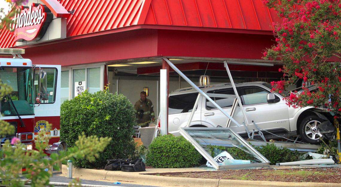 A Wilson, N.C., Fire/Rescue Services firefighter stands behind a sport utility vehicle that crashed into a Hardee’s restaurant on Sunday, Aug. 14, 2022, in Wilson, N.C. The Wilson Police Department is investigating the wreck, from which it said two customers inside the restaurant died. (Drew C. Wilson/The Wilson Times via AP)