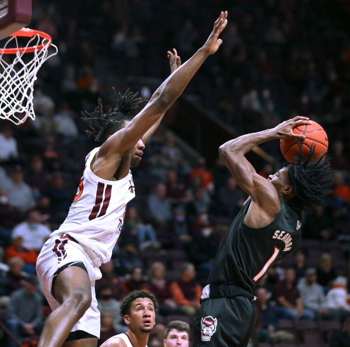 Virginia Tech’s Justyn Mutts (25) defends against North Carolina State’s Dereon Seabron (1) in the first half of an NCAA college basketball game Tuesday, Jan. 4, 2022, in Blacksburg, Va. (Matt Gentry/The Roanoke Times via AP)