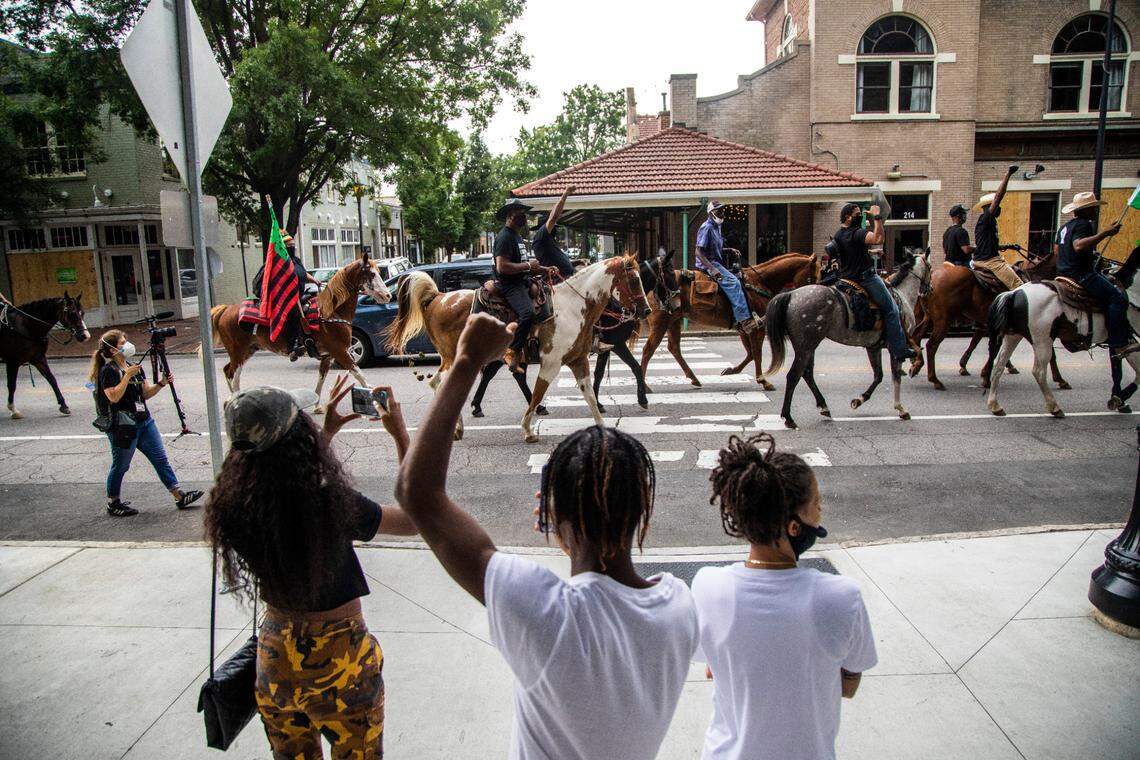 People cheer on Black Lives Matter demonstrators as they ride on horseback through downtown Raleigh Friday, June 19, 2020 in recognition of Juneteenth.