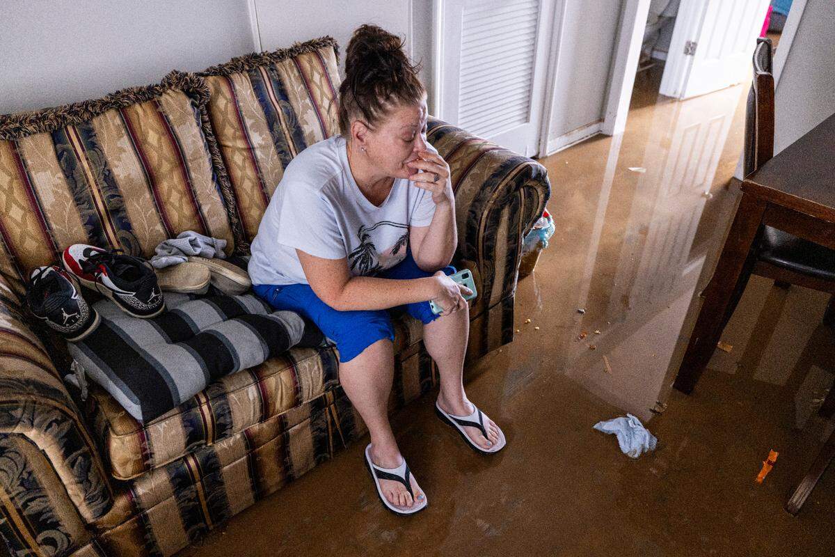 Jennifer Lyles, 46, is overwhelmed as she sits in the living room of her Rippling Streams Townhome in the Old Farm neighborhood along the Eno River in Durham on July 7, 2025. Lyles said she was awakened by firefighters in a boat around 2:30 a.m.