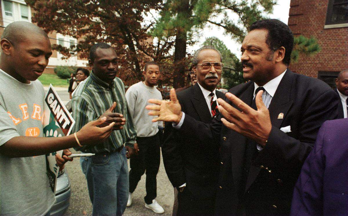 Jesse Jackson says to NCCU students at left that he can't stay and shake hands, sign autographs and talk though he would like to as he has to catch a flight right away Wed. am after speaking at a get out the vote rally at B. N. Duke auditorium on campus in 1996.