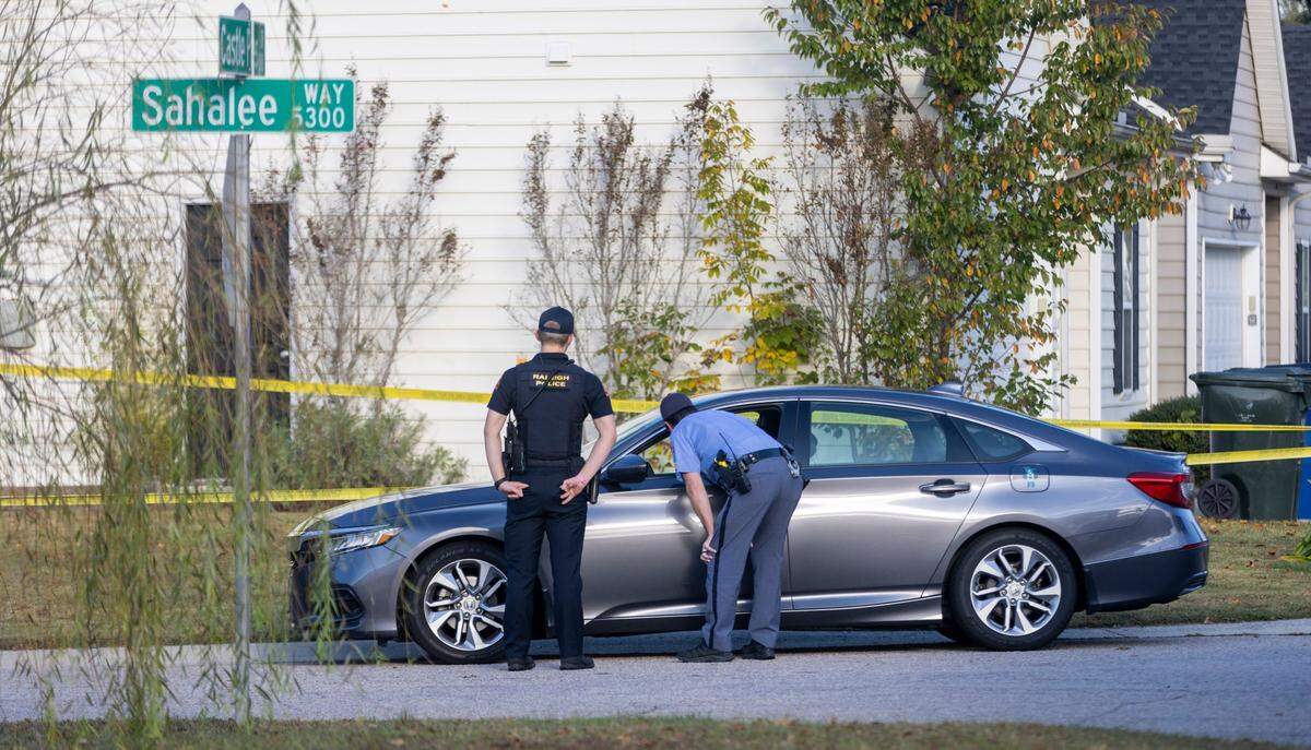 Raleigh Police talk with a motorist on Sahalee Way in the Hedingham neighborhood on Friday morning, October 14, 2022 in Raleigh, N.C. as they continue to investigate the killing of five people yesterday on the greenway nearby.
