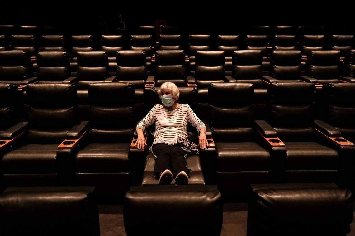A woman waits for a movie to start at a Regal movie theater in Irvine, Calif., Tuesday, Sept. 8, 2020. Starting Oct. 2, 2020 in North Carolina, movie theaters can open at 30% capacity per screen.