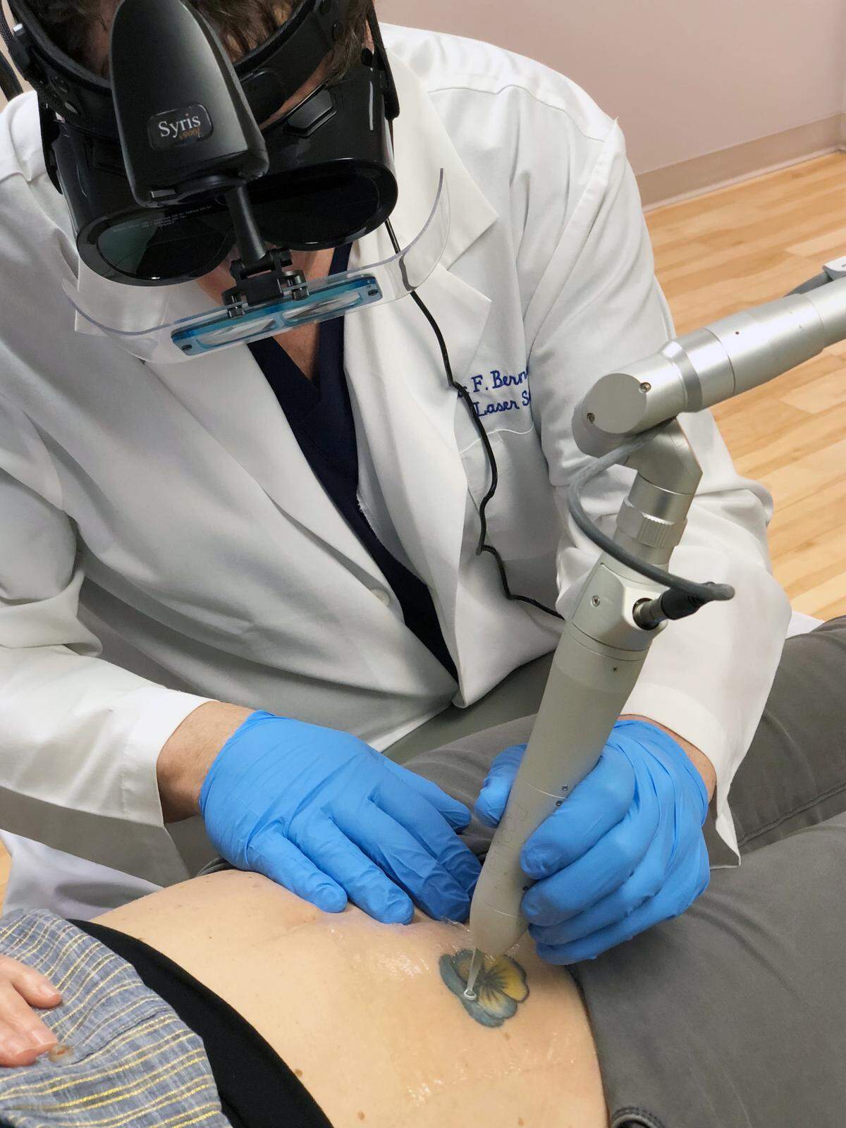 Dr. Eric Bernstein, dermatologist and director of Mainline Center for laser surgery, uses a laser to remove a tattoo from a client’s abdomen.