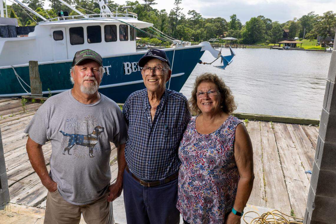 Timmie Millis, left, is a commercial shrimper. He stands near the dock at the shore of Wheeler Creek in Sneads Ferry with his father, Tim Millis, and sister, Nancy Edens, who manages the family’s business, B.F. Millis & Sons Seafood.