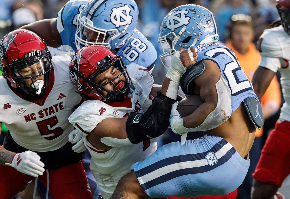 N.C. State defensive end Davin Vann (1) tackles North Carolina running back Omarion Hampton during the first half of N.C. State’s game against UNC at Kenan Stadium in Chapel Hill, N.C., Saturday, Nov. 30, 2024.
