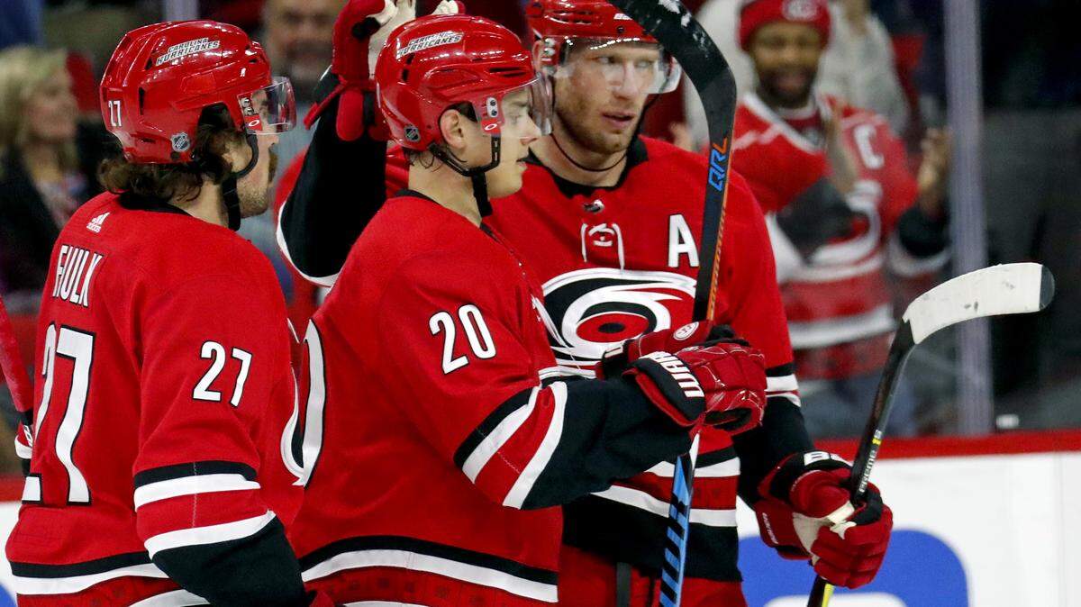 The Canes’ Sebastian Aho (20) celebrates his goal with Justin Faulk (27) and Jordan Staal (11) during the first period.
