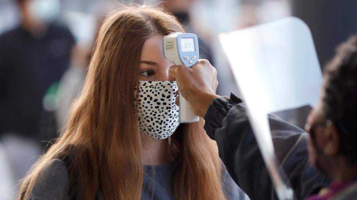 Allison Dempsey, a junior at Millbrook High School in Raleigh, N.C., gets her temperature checked before entering the school Wednesday morning, February 17, 2021. Wednesday is the the first day of face-to-face classes since March 2020 for Wake County high school students.