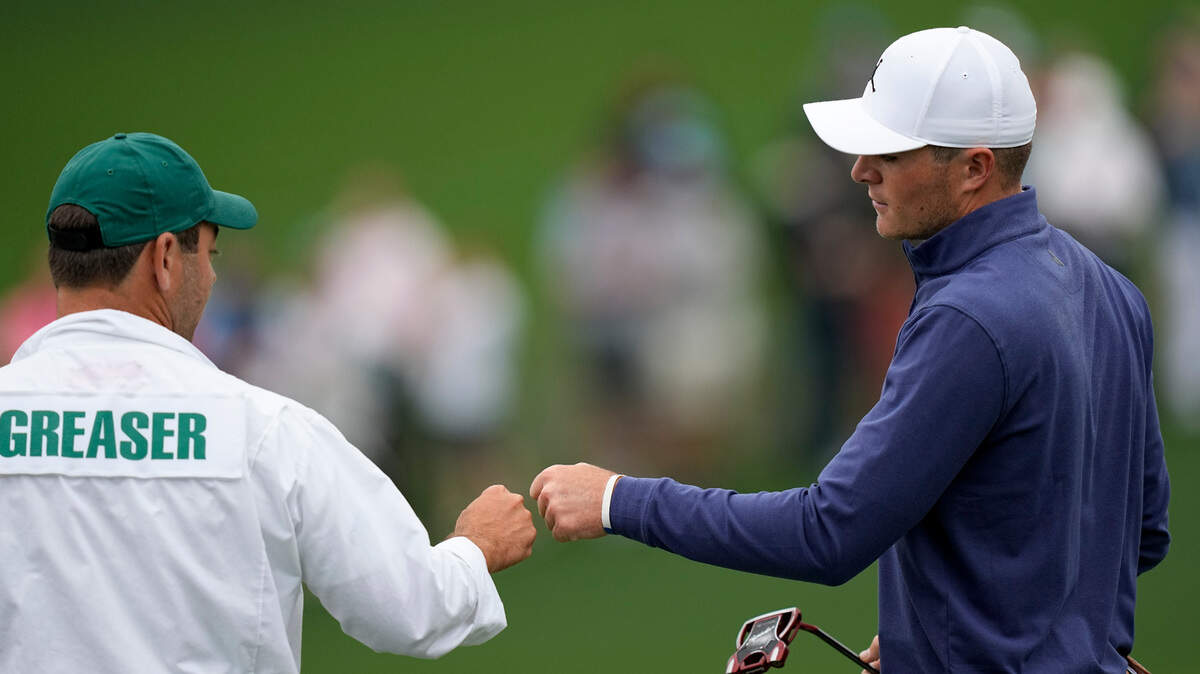 Amateur, Austin Greaser bumps fists with his caddie Andrew DiBitetto after a birdie on the second hole during the first round at the Masters golf tournament on Thursday, April 7, 2022, in Augusta, Ga. (AP Photo/David J. Phillip)