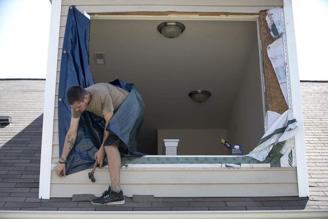Tommy Hall III works to hang a tarp over an upstairs window that was blown out of his home on Slippery Rock Way in The Farm at Brunswick subdivision on Friday, September 6, 2019 in Carolina Shores, N.C. Forty homes were damaged by a tornado spawned by Hurricane Dorian on Thursday morning, September 5, 2019.